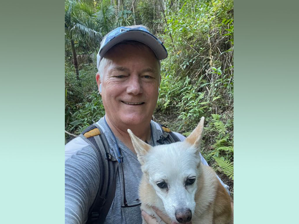 Brenden Holland, Ph.D., with his dog on a forest trail in Hawai'i