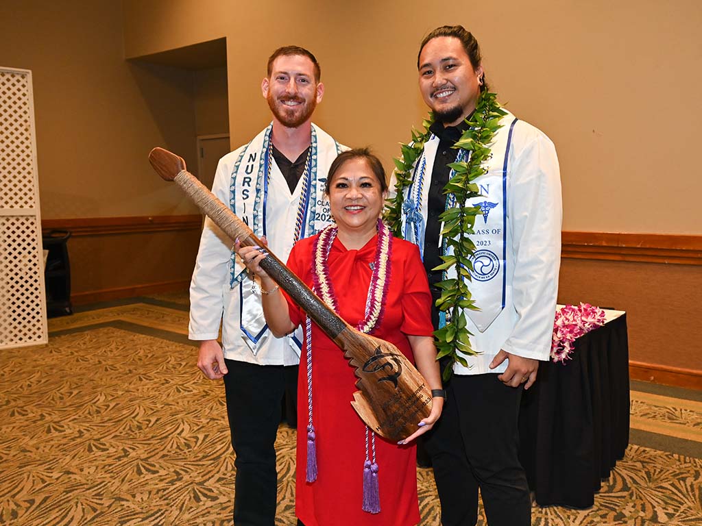 Dean Magpantay-Monroe holds the class gift of a paddle made of monkey pod wood