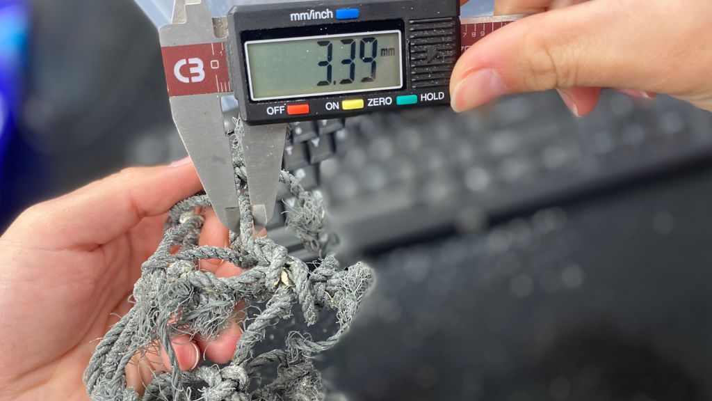 A HPU CMDR researcher measures the twine diameter of the net, which can help to identify the fisheries that might have used the net before it was lost or abandoned in the ocean.