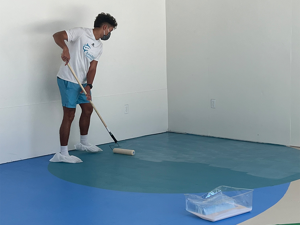 Student Worker, Elijah, helps paint the floor at the Makerspace
