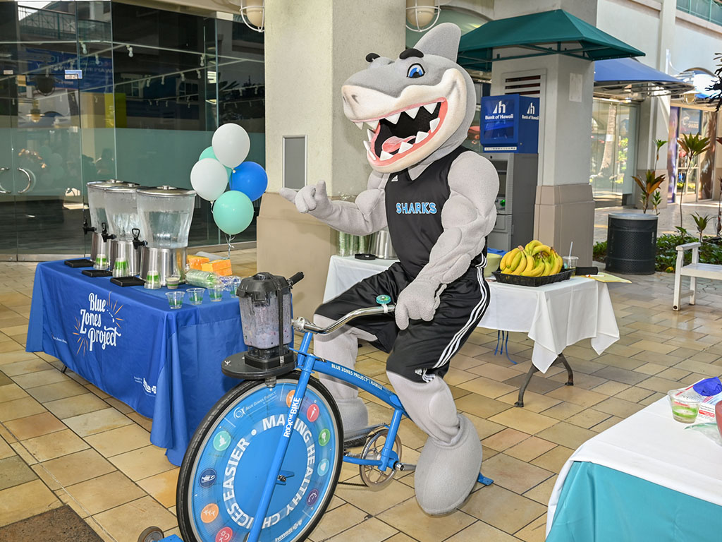 Sharky rides the blender bike at the celebration event at Aloha Tower Marketplace