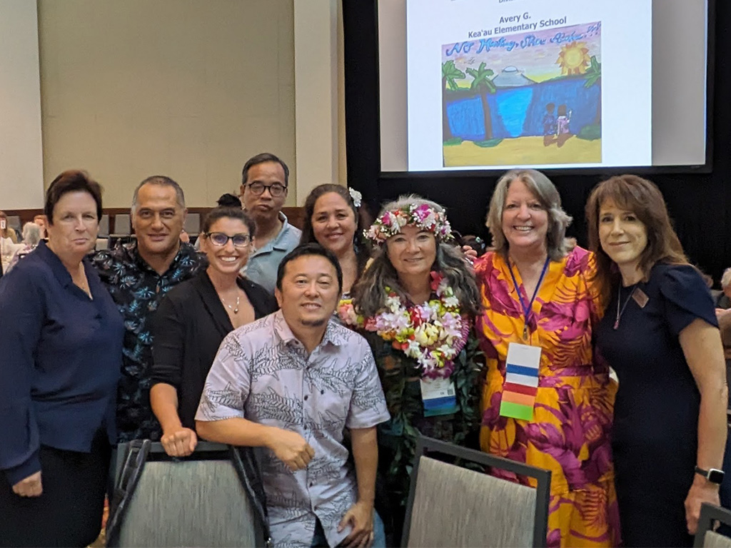 School of Social Work faculty and Senior Vice President and Provost Jennifer Walsh, Ph.D., (far right) and College of Liberal Arts Dean Allison Gough, Ph.D., (far left) join in congratulating Lori Daniels, Ph.D., (with lei) on receiving the Institute on Violence and Abuse and Trauma Hawaii Summit Lifetime Achievement Award at the organization's April 10 summit luncheon