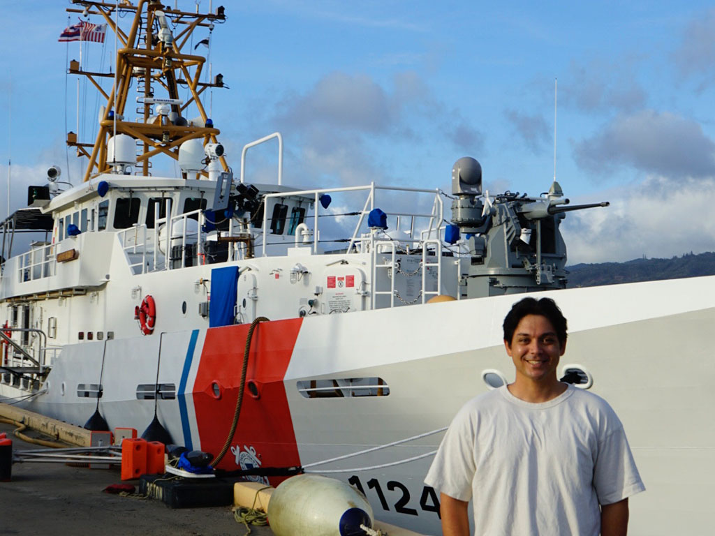 Noah Eddins pictured in front of a U.S. Coast Guard Cutter