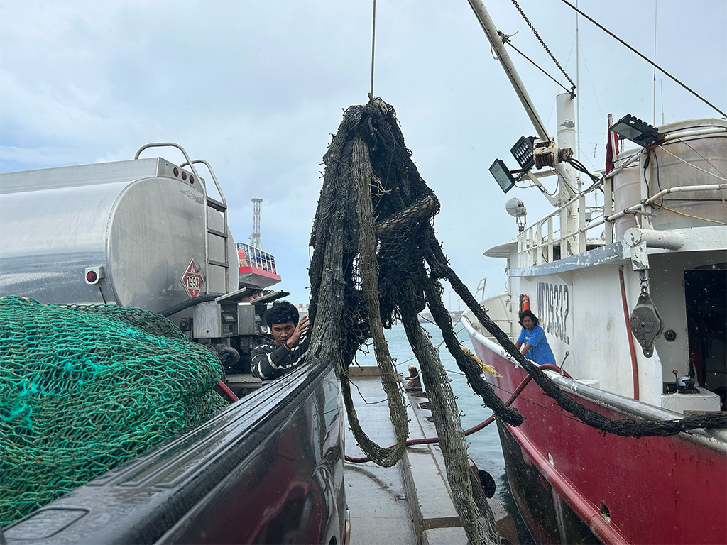 Fishermen hauling derelict fishing gear from the ocean to the shore