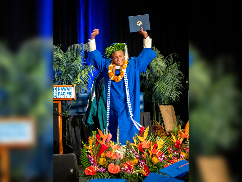 A graduate celebrates while walking across the stage upon receiving his degree