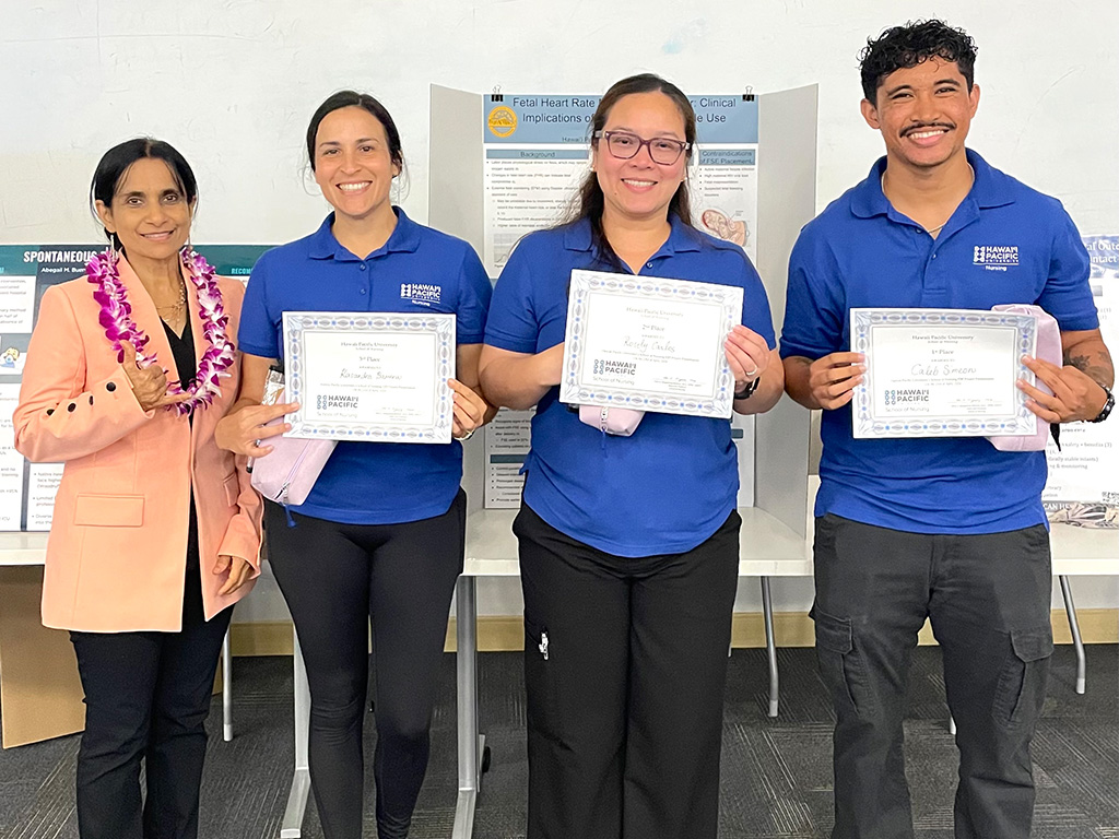 HPU nursing students (left to right) Kasandra Barerra, Rosely Carlos, and Caleb Simeon pose with Hazel Dowing, during the Spring 2026 Evidence-Based Practice Showcase at Aloha Tower Marketplace