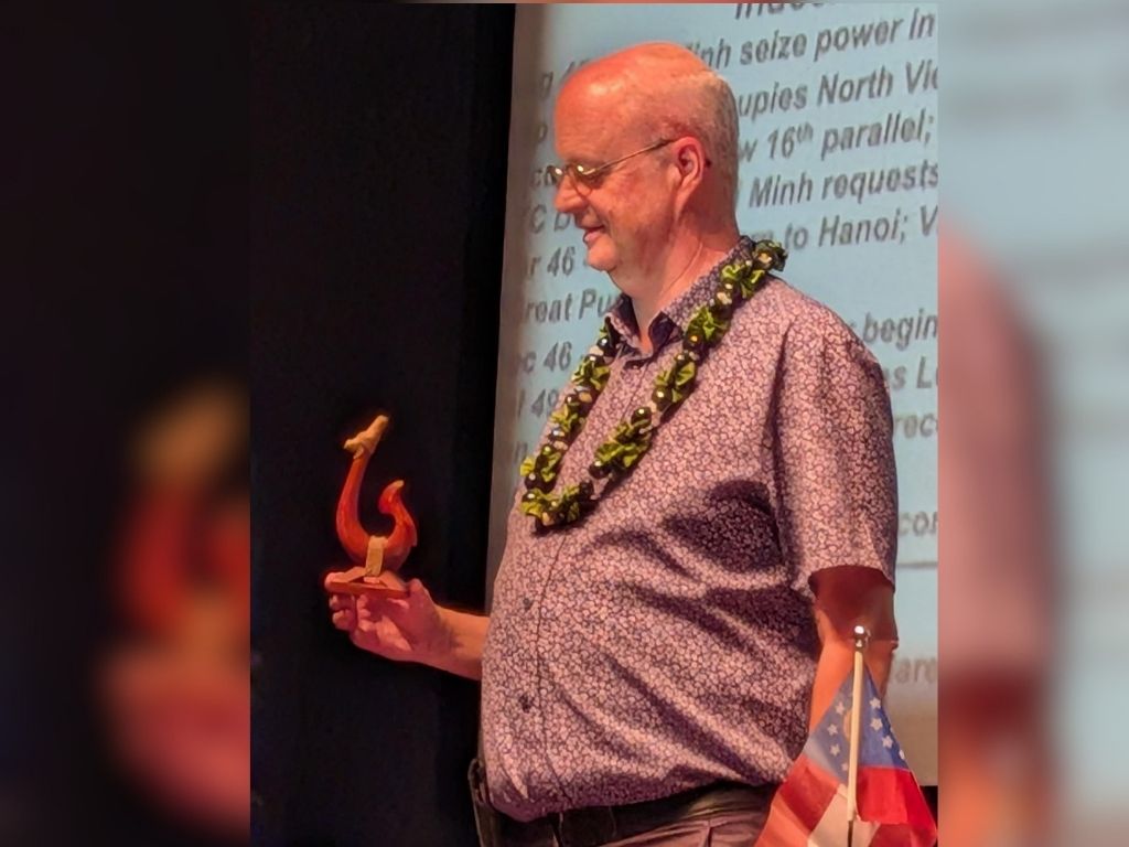 Russell Hart, Ph.D., holds the carved koa gift he received from the organizers of the Journey to Peace Hawaii initiative in recognition of his participation in the forum 