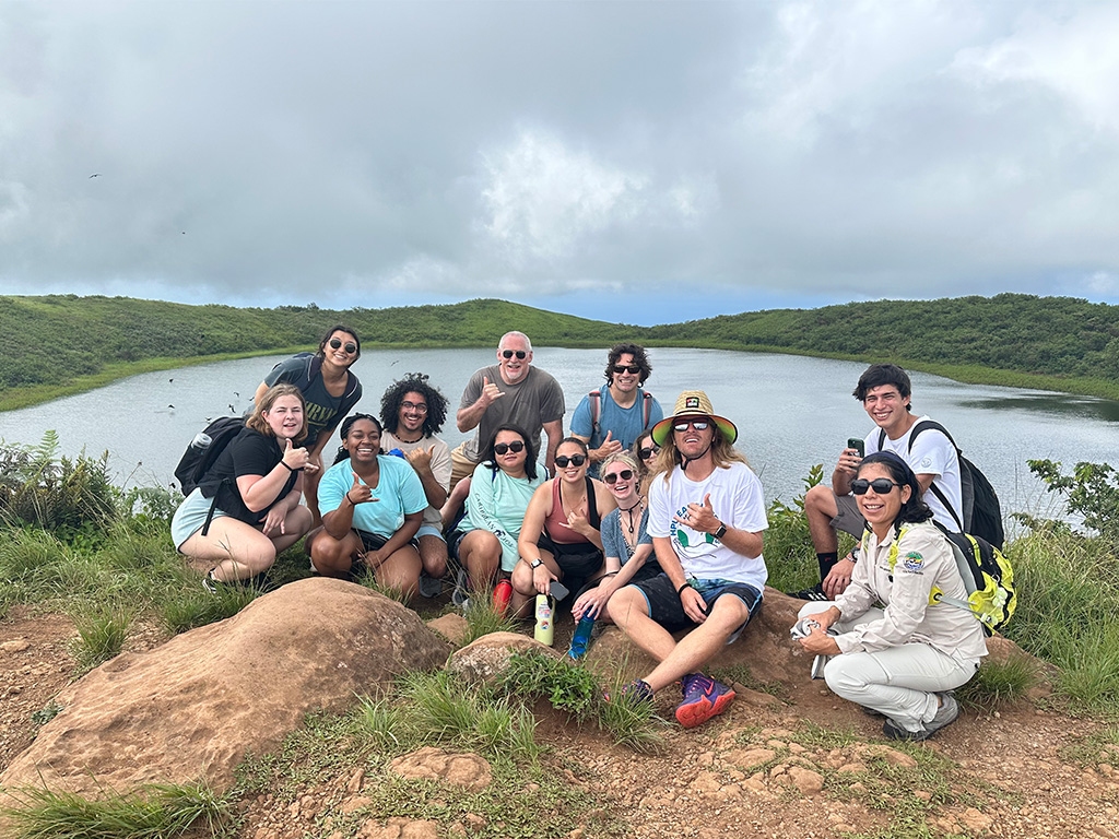 HPU students take in El Junco Lagoon, the only permanent freshwater lake in the Galapagos and a spot where frigatebirds come to rinse salt from their feathers. The study abroad trip, organized by HPU Assistant Professor Adam Burke (center, in the straw hat), gives MASUST students the chance to analyze sustainable features in another tourism-dependent archipelago in the Pacific