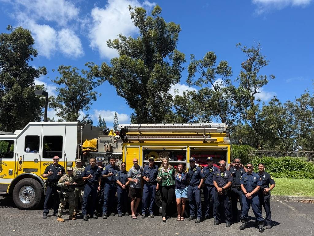 Jacque Bucher, wearing lei and denim shorts, with State Senator Danielle Bass, Founder and CEO of Malama Pono Autism Center Matt Brink, and first responders at the Autism Awareness and Community Safety event in Mililani 